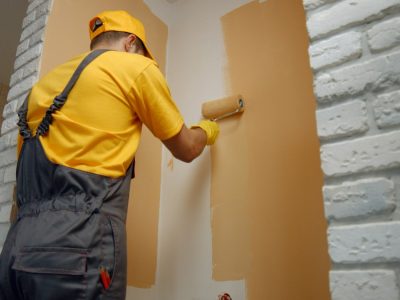 Worker painting wall with paint roller. Worker painting wall with paint roller.